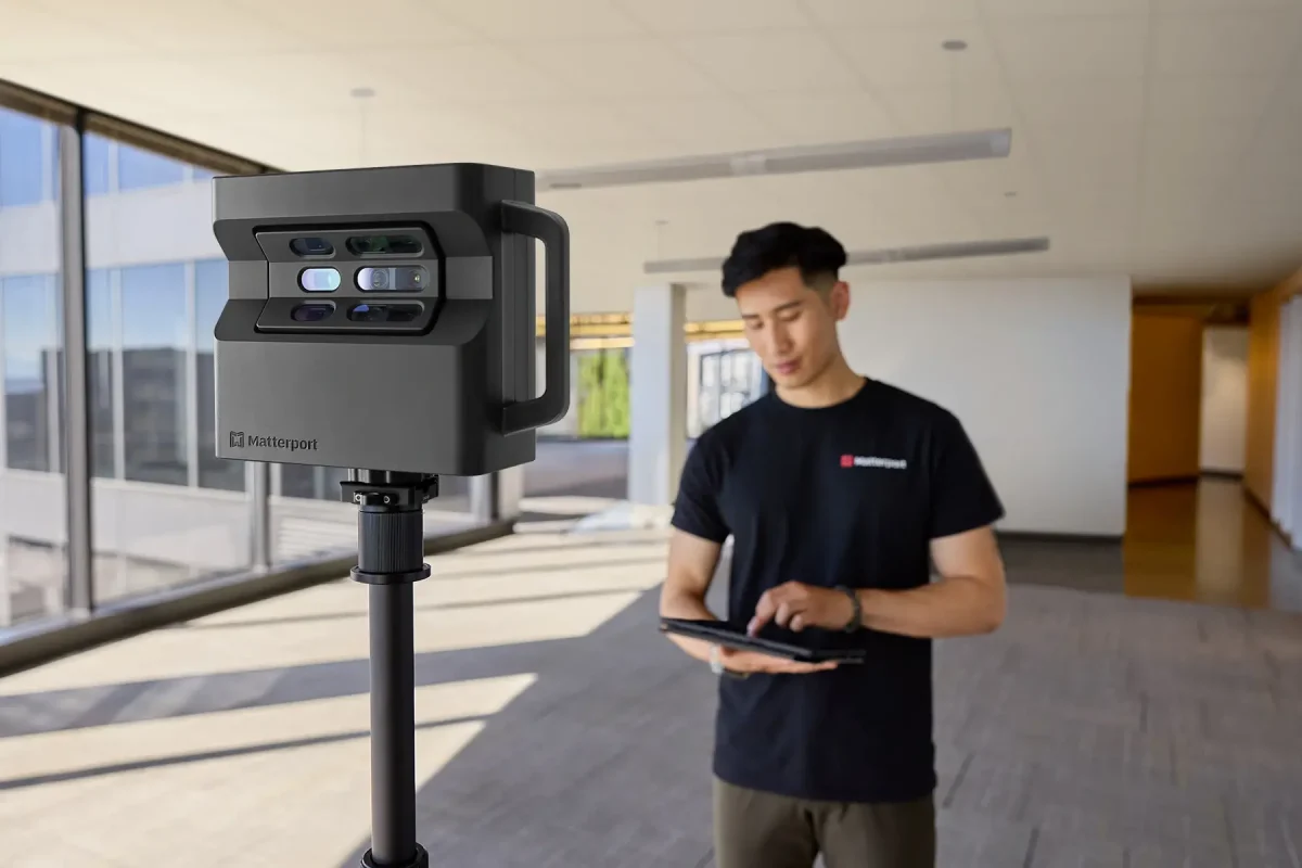 a man holding a tablet in front of a matterport pro2 stand