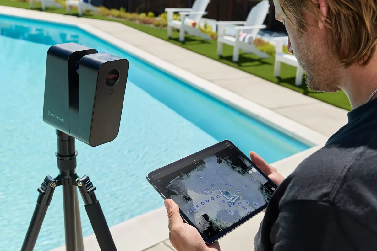a man holding a tablet in front of a matterport pro3 Lidar Camera stand