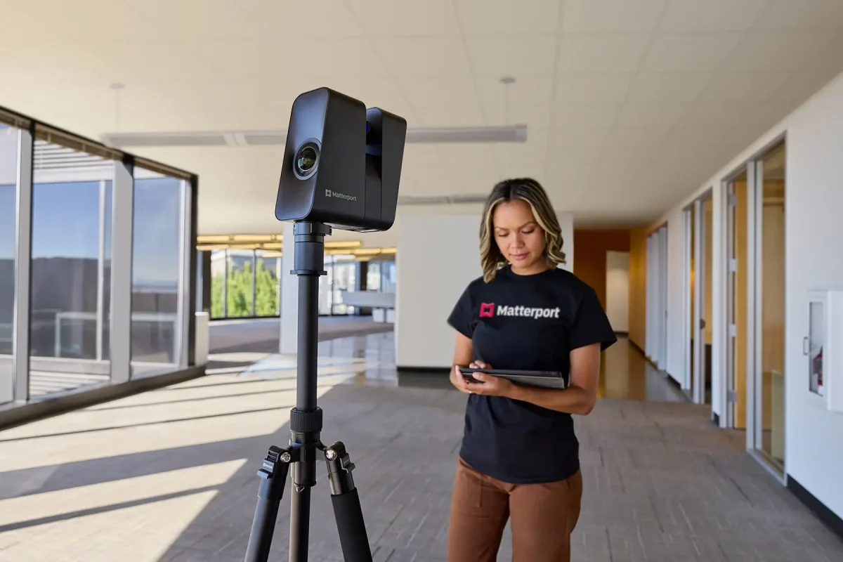 a woman holding a tablet in front of a matterport pro3 Lidar Camera stand